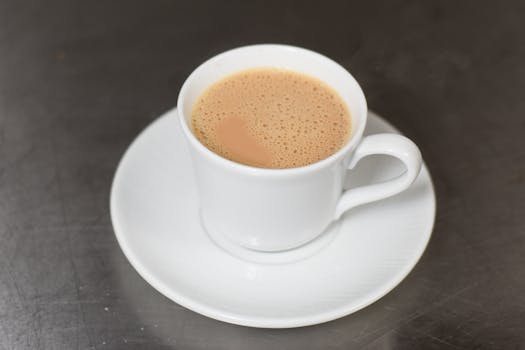 A detailed view of a frothy cappuccino served in a white cup and saucer.